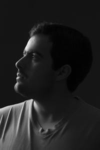 Black and white portrait of a man gazing aside, emphasizing shadows.